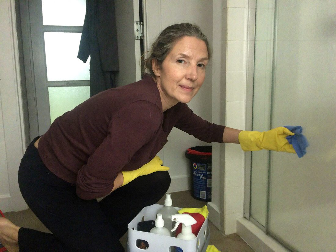Frau putzt kniend eine Dusche