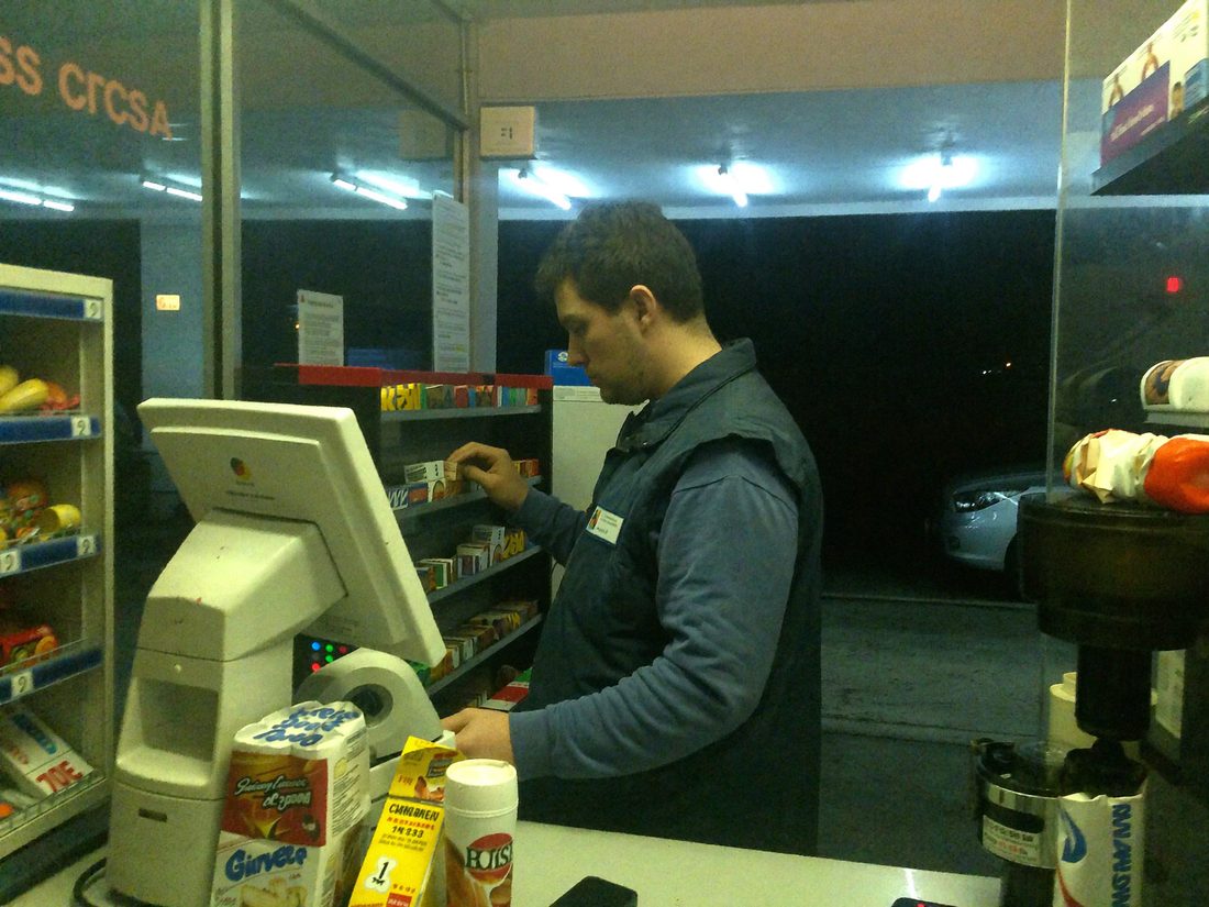 Mann räumt nachts ein Regal an der Tankstelle ein